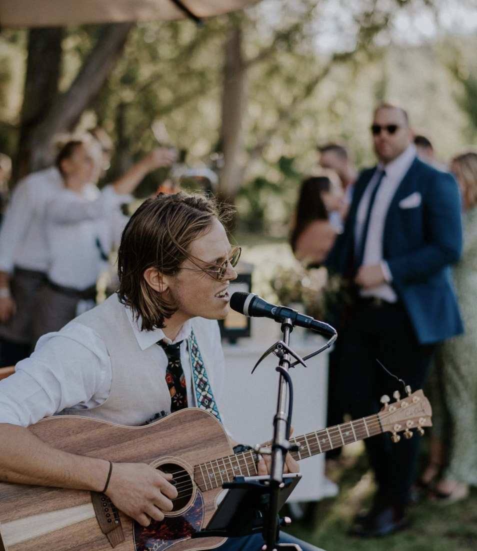 Mitch playing acoustic guitar and singing at an outdoor wedding